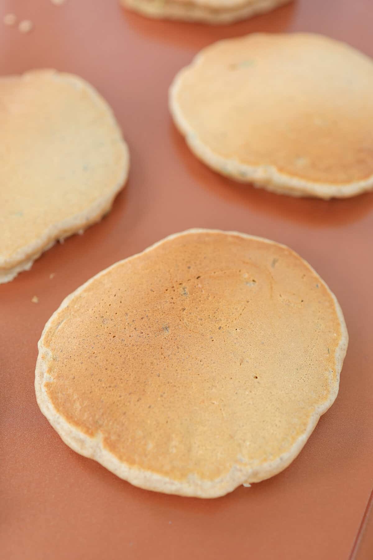 Zucchini pancakes cooking on a griddle.