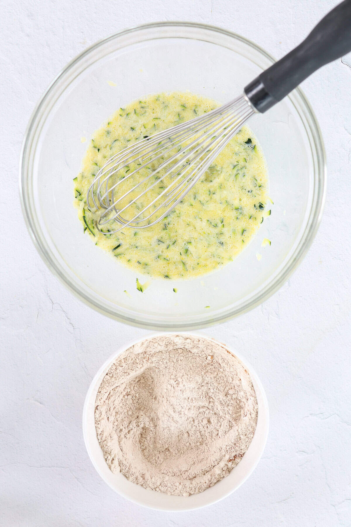 A bowl of wet ingredients and a bowl of dry ingredients for pancakes sitting side by side.