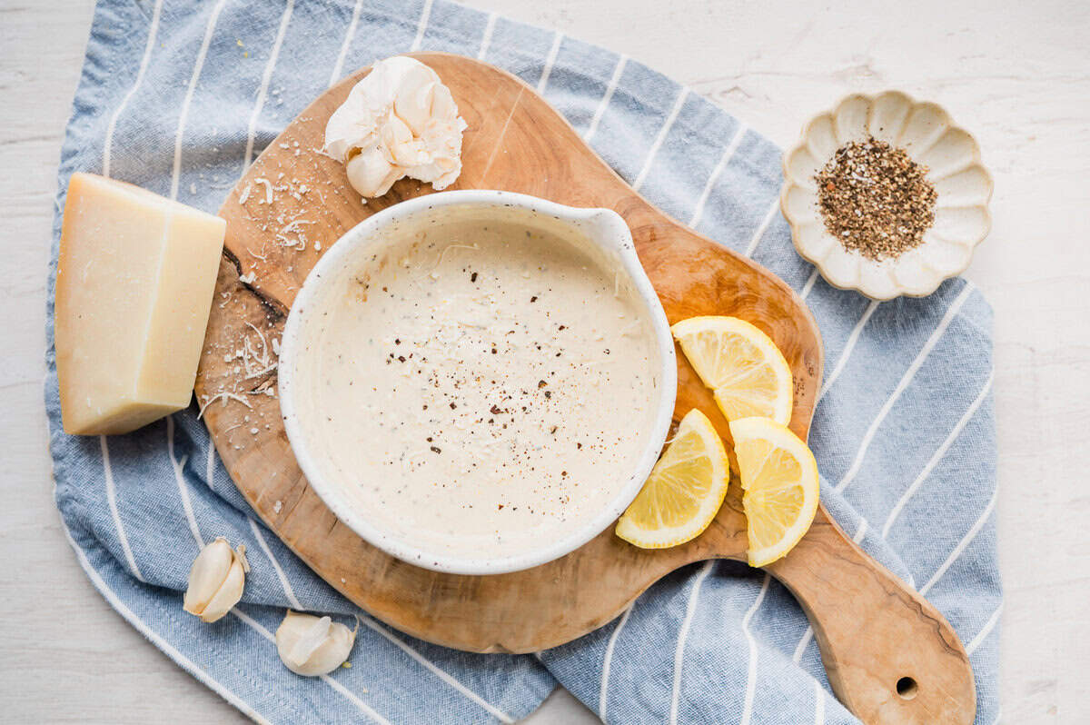 Homemade Caesar dressing in a bowl with pouring lip.