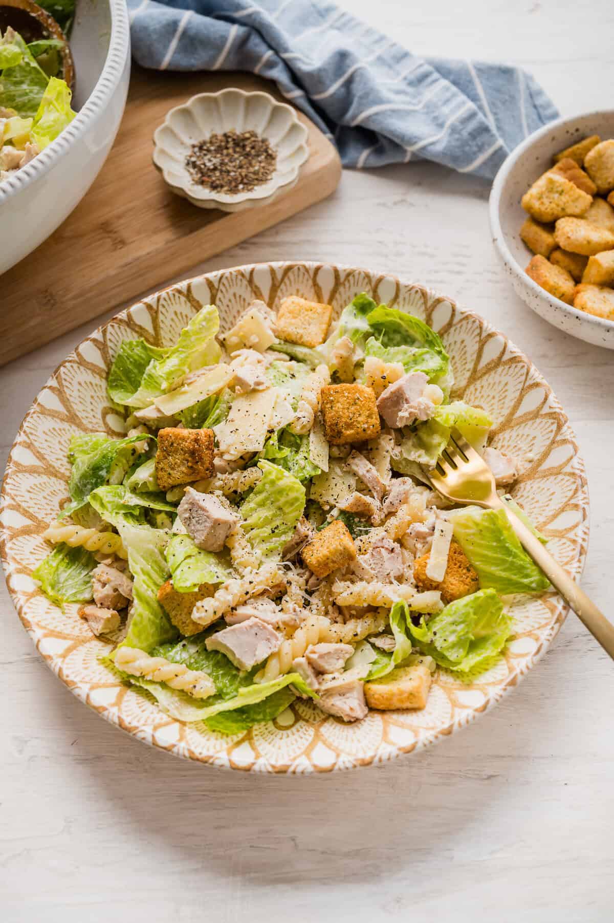 Caesar pasta salad in a dish with a fork ready to eat.