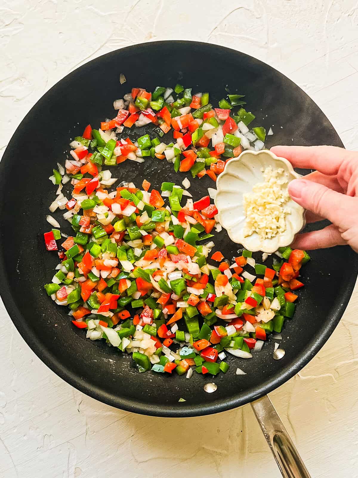 Diced bell peppers and onions in a skillet.