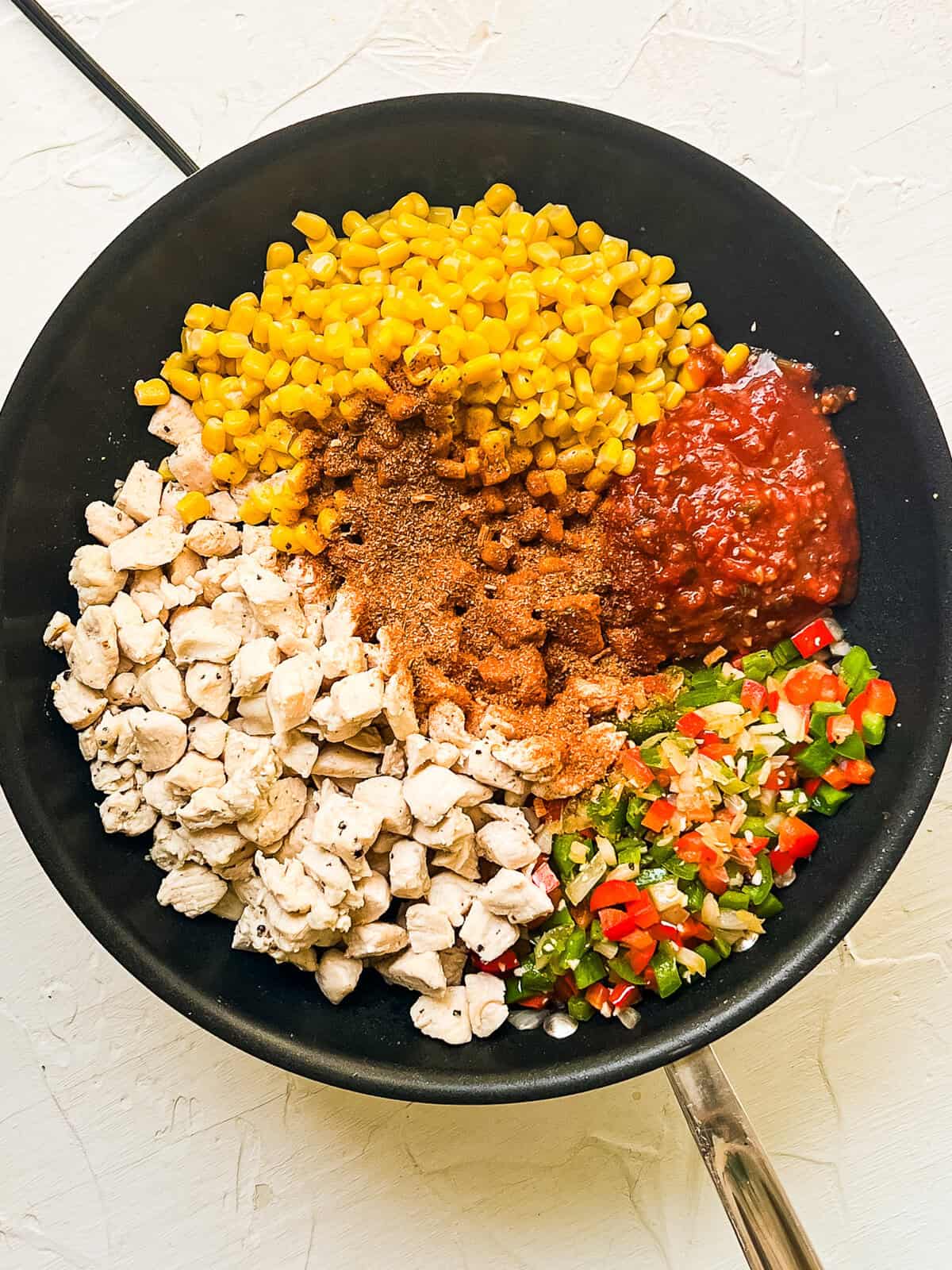 Ingredients for chicken fajita casserole in a skillet.