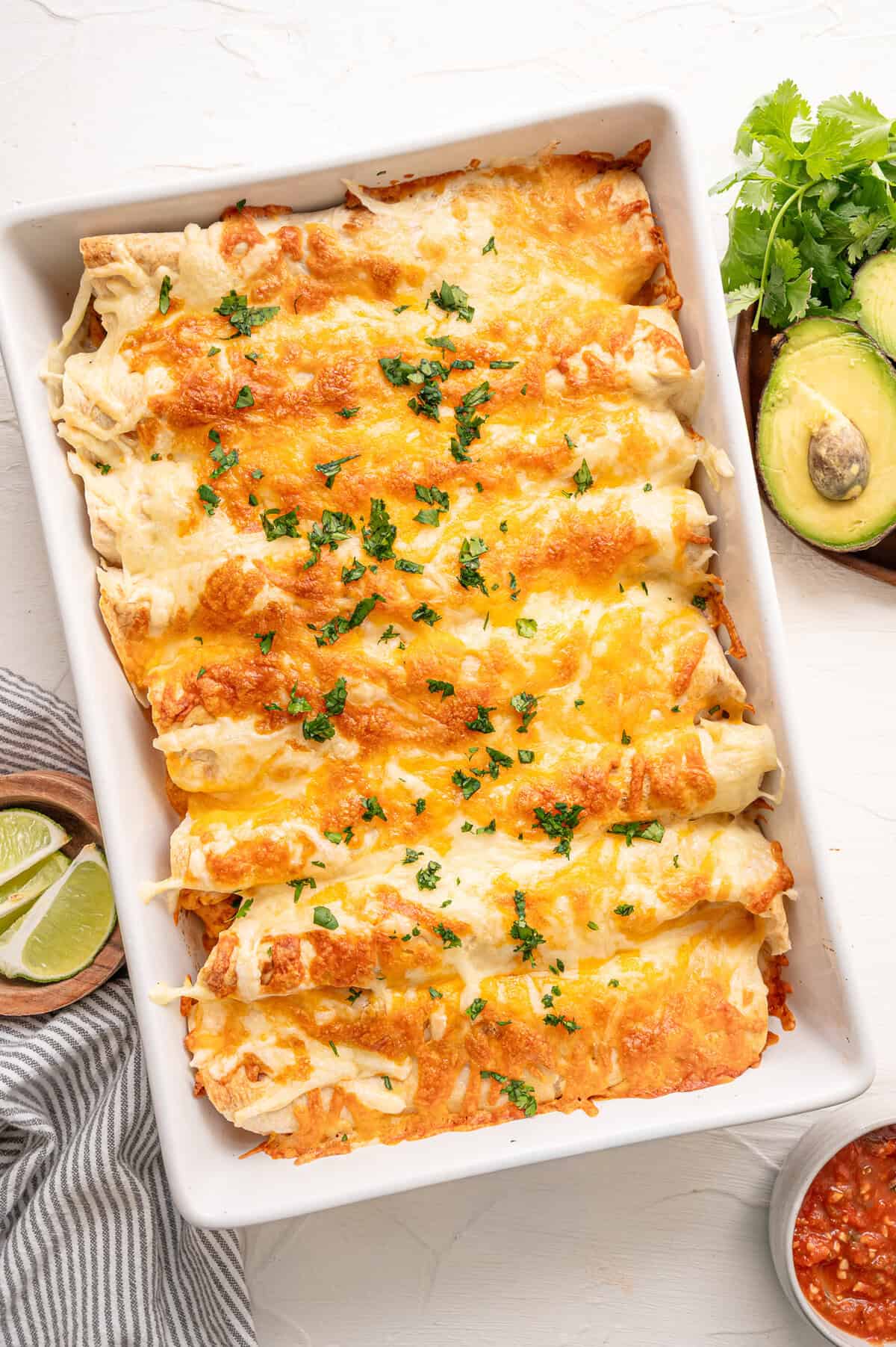 Fully cooked chicken fajita casserole in a white baking dish topped with parsley.