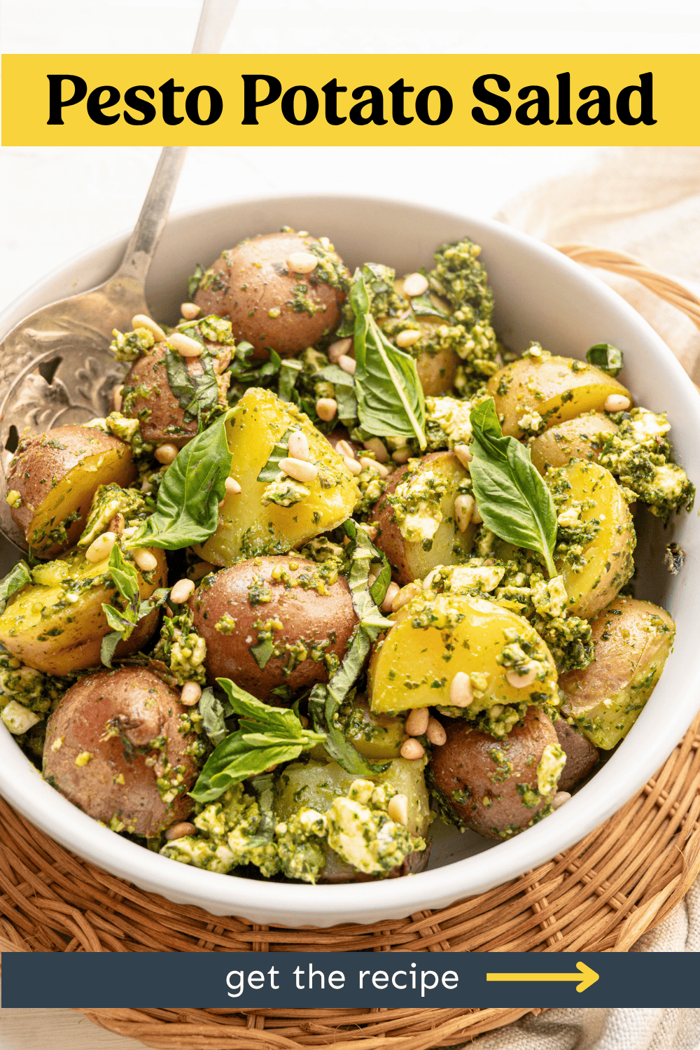 A bowl of pesto potato salad in a white bowl on a wicker basket.