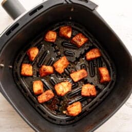 Salmon bites in an air fryer basket after being cooked.