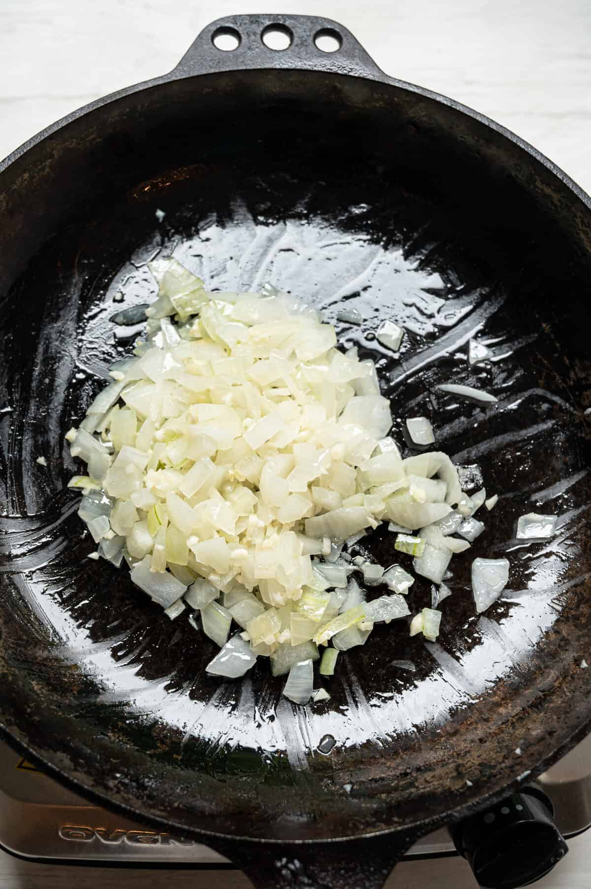 Diced onion sauteing in a cast iron skillet.