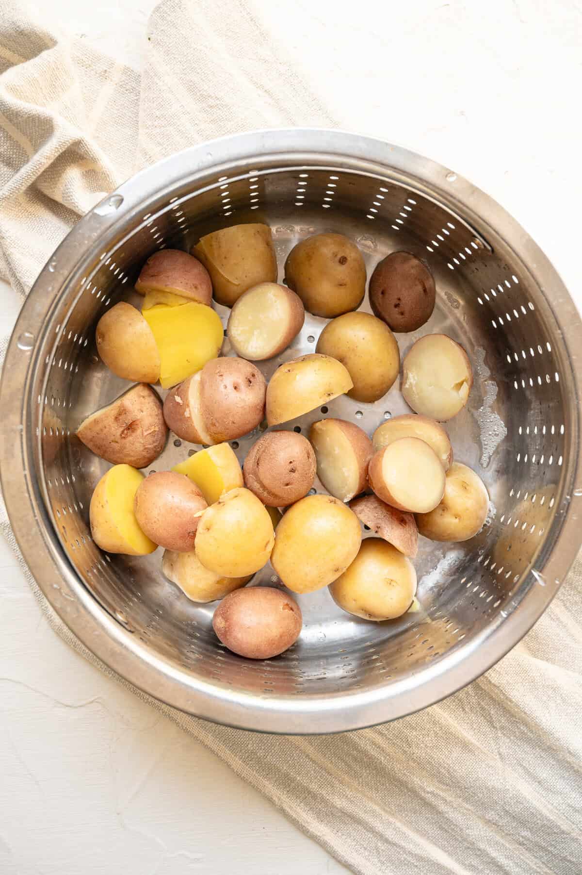 Baby potatoes being drained in a metal colander.
