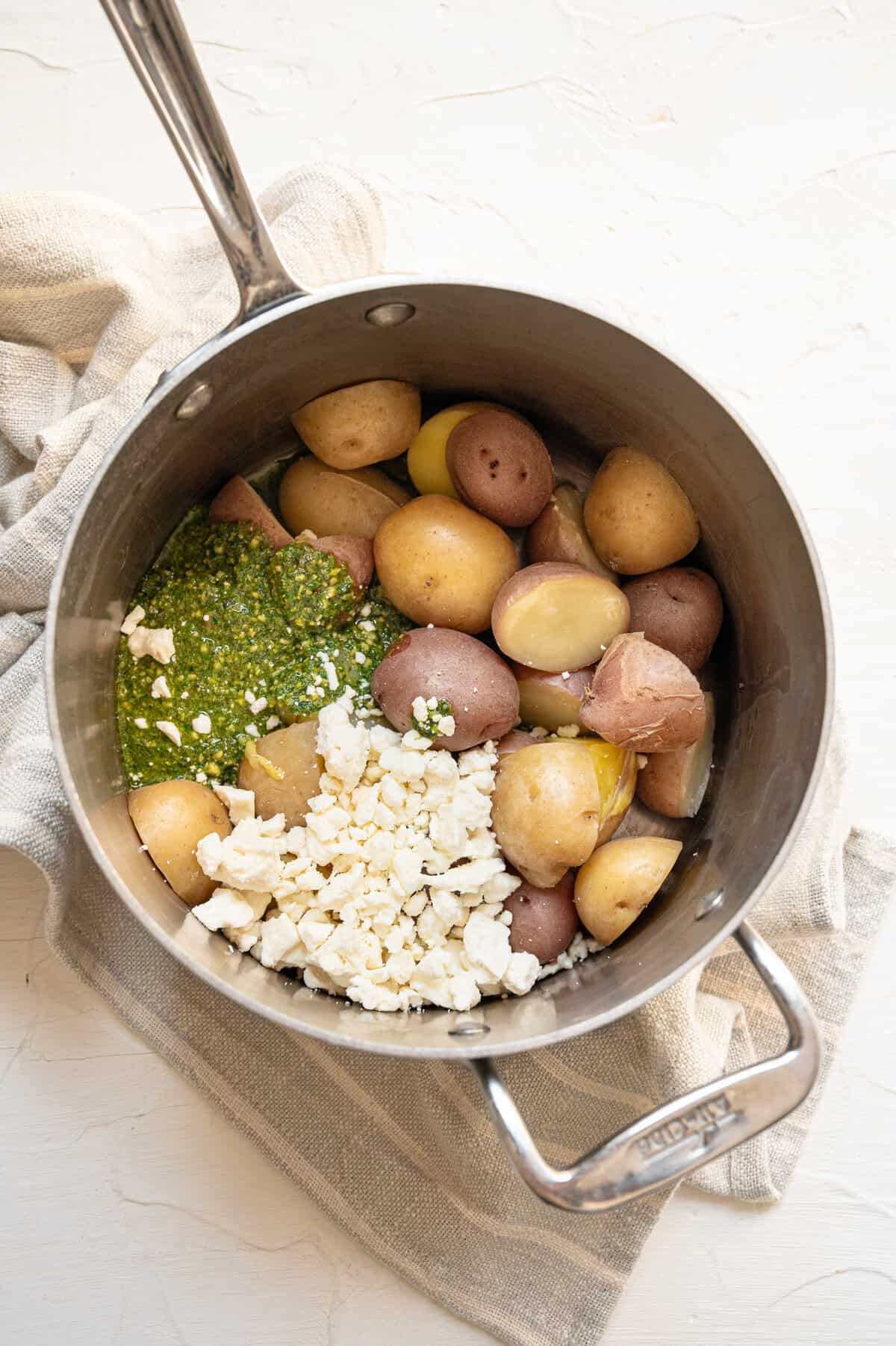 Sauce pan with cooked baby potatoes, Feta cheese, and pesto piled in.