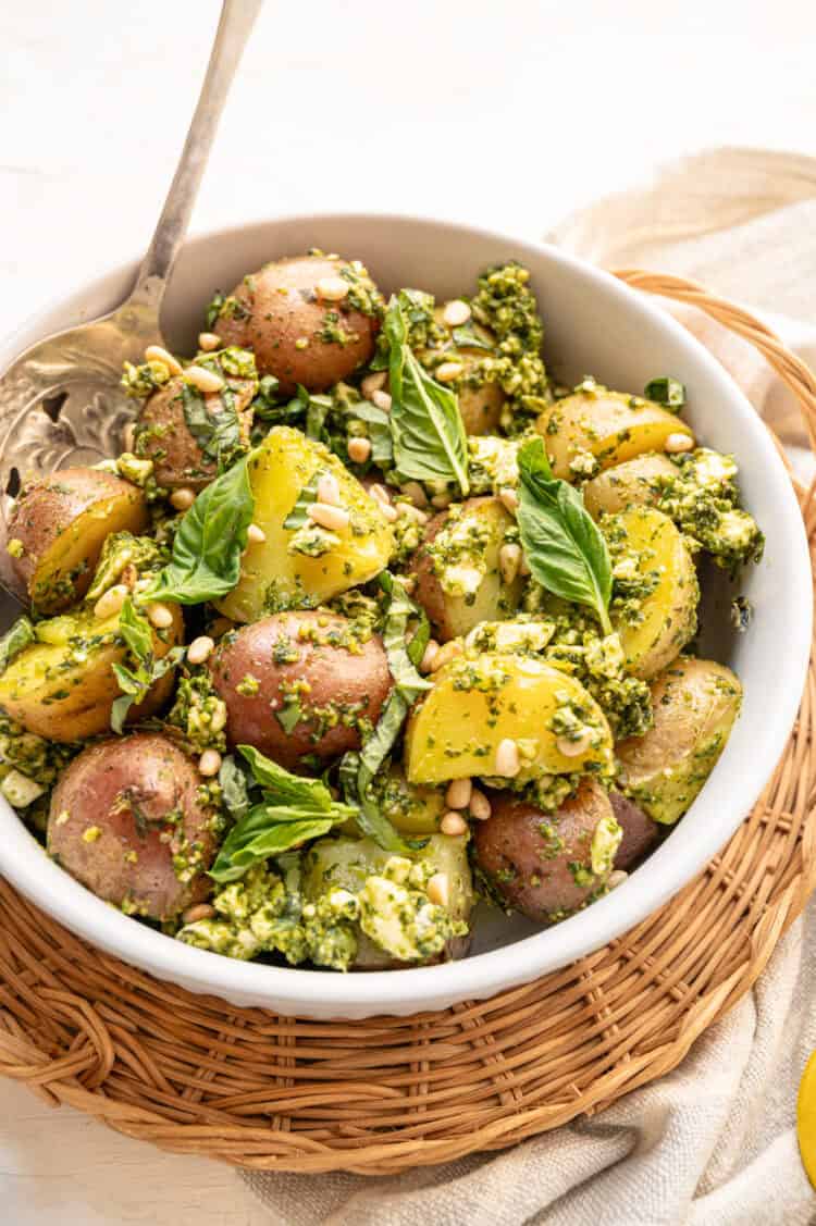 Pesto potato salad served with fresh basil and pine nuts on top.