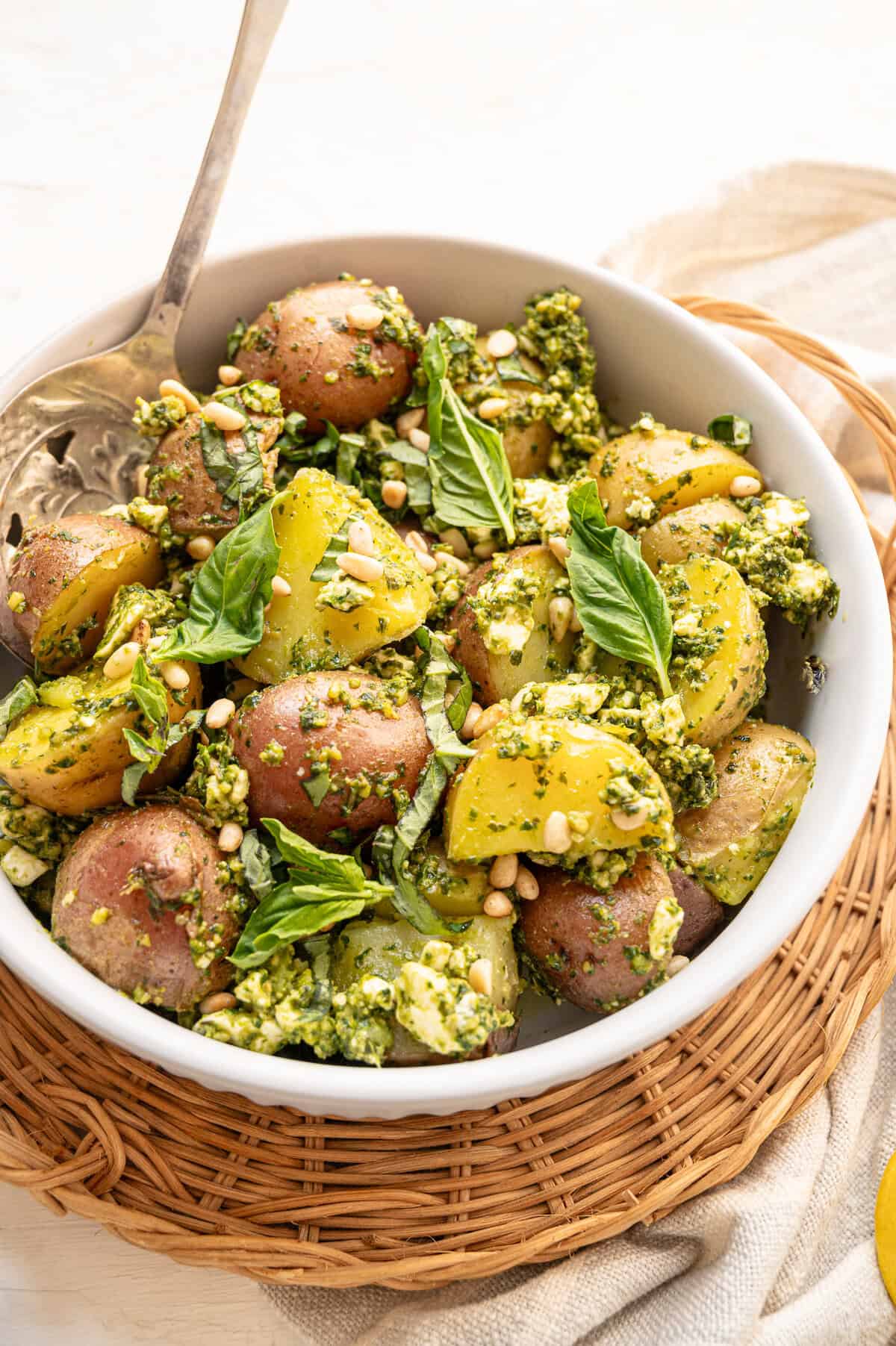 Pesto potato salad served with fresh basil and pine nuts on top.