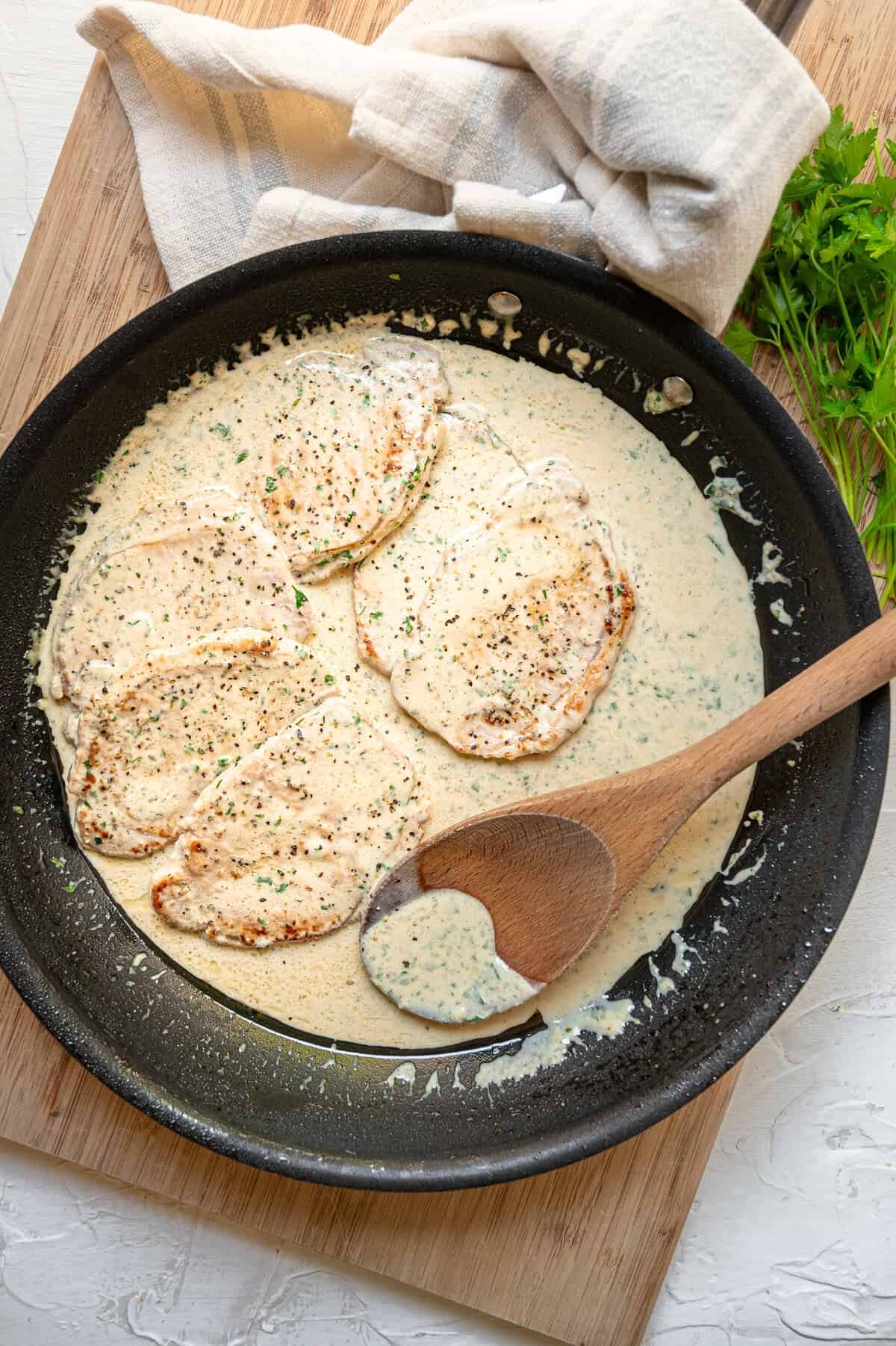 Pan of creamy Boursin pork chops in a skillet with fresh parsley