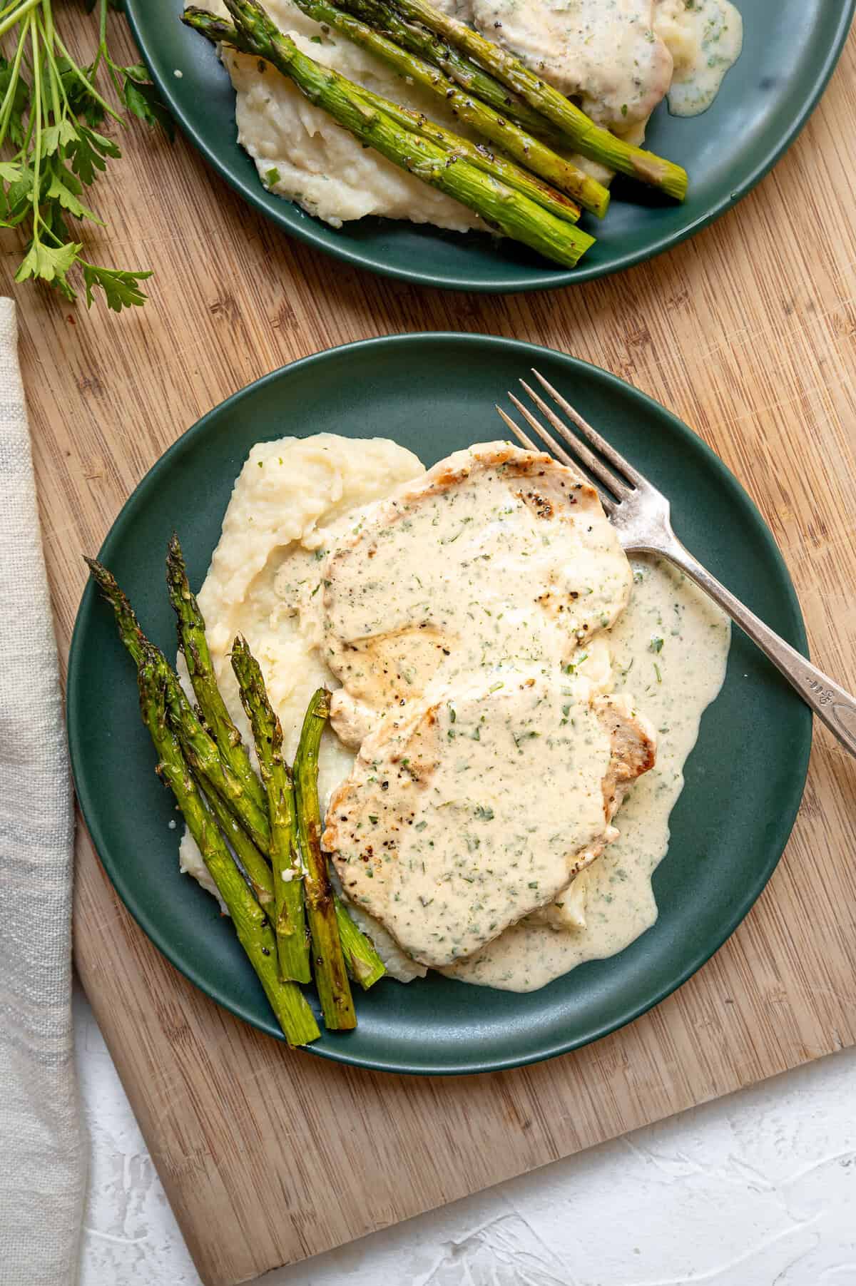 Plates of creamy Boursin pork chops with mashed potatoes and asparagus