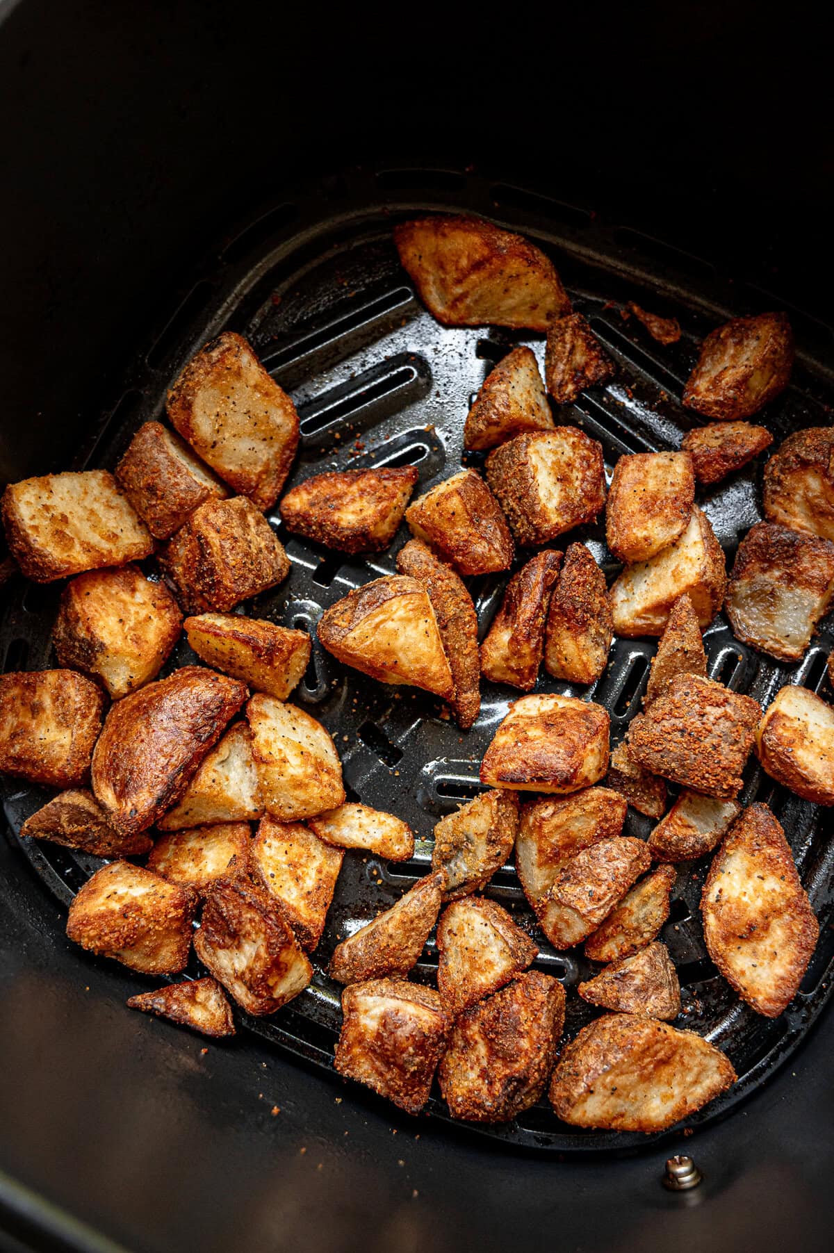 Frozen potatoes roasted in an air fryer basket.