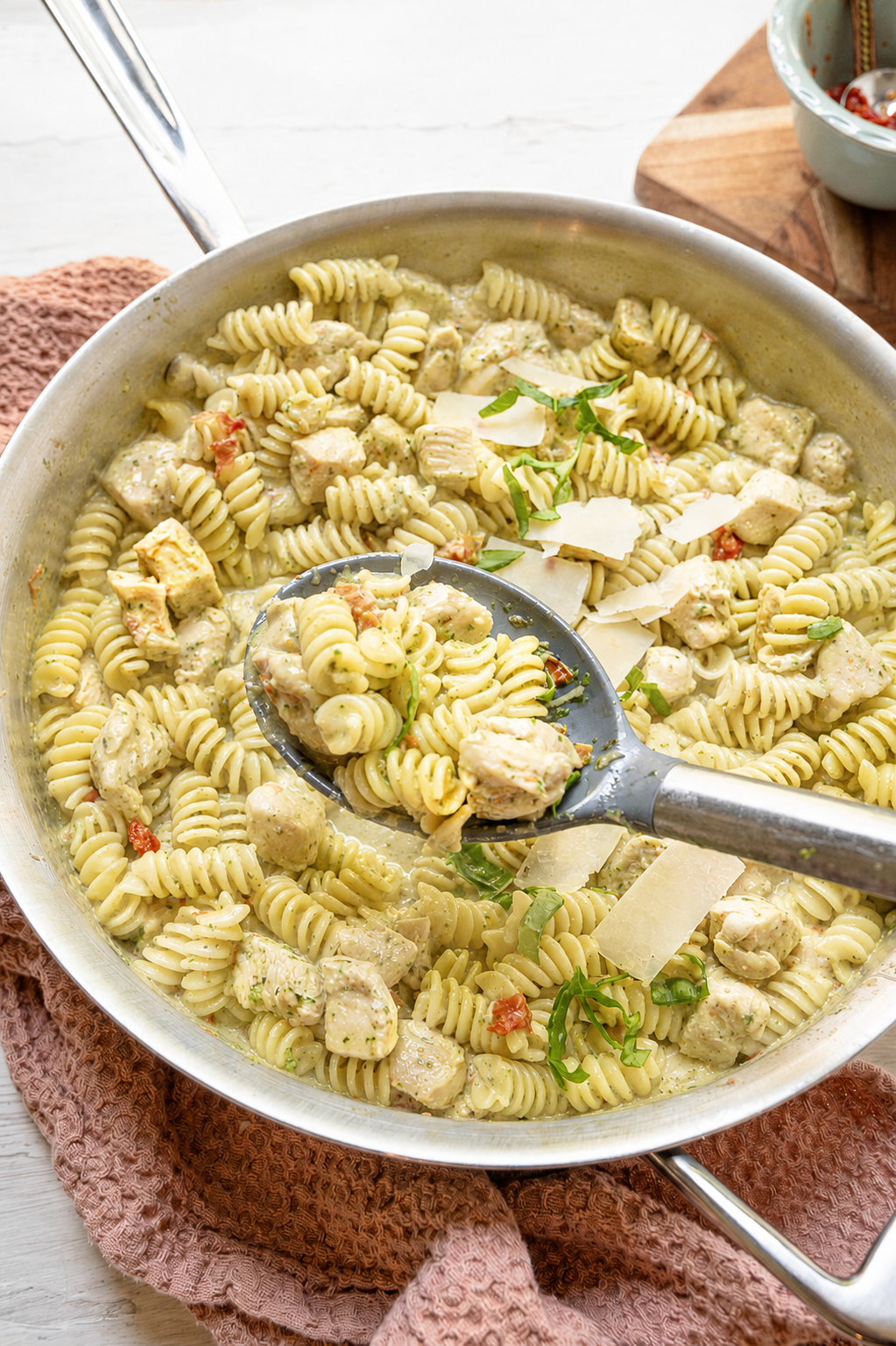 Creamy chicken pesto pasta being served from the skillet.