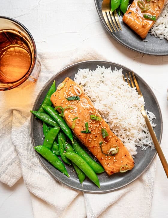 A plate with rice, steamed snap peas, and a baked Asian salmon filet.