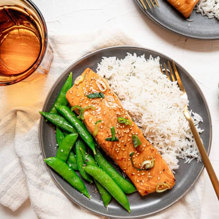 A plate with rice, steamed snap peas, and a baked Asian salmon filet.