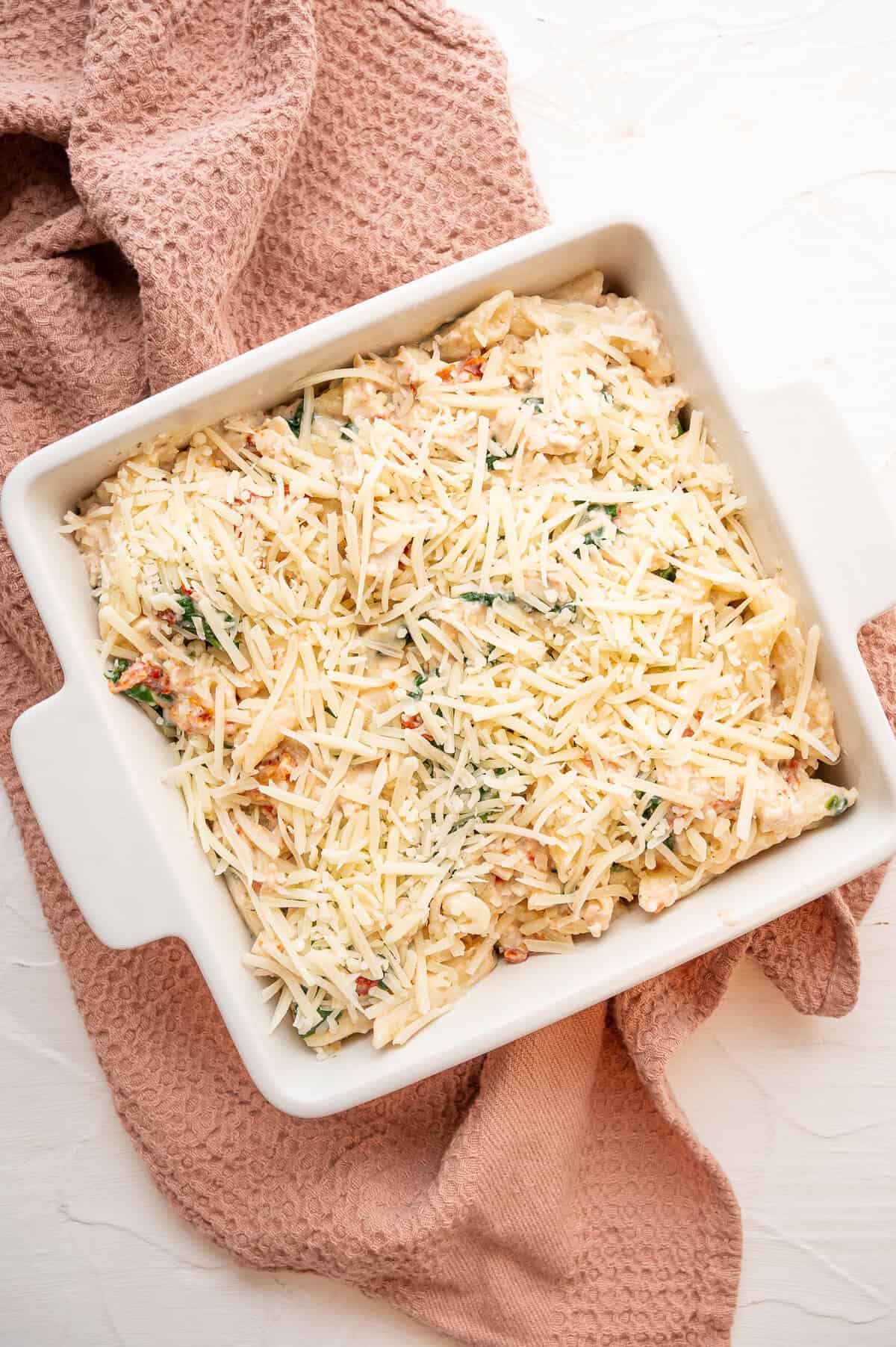 Marry me chicken casserole in a 9x9 baking dish with shredded mozzarella on top ready to be baked.
