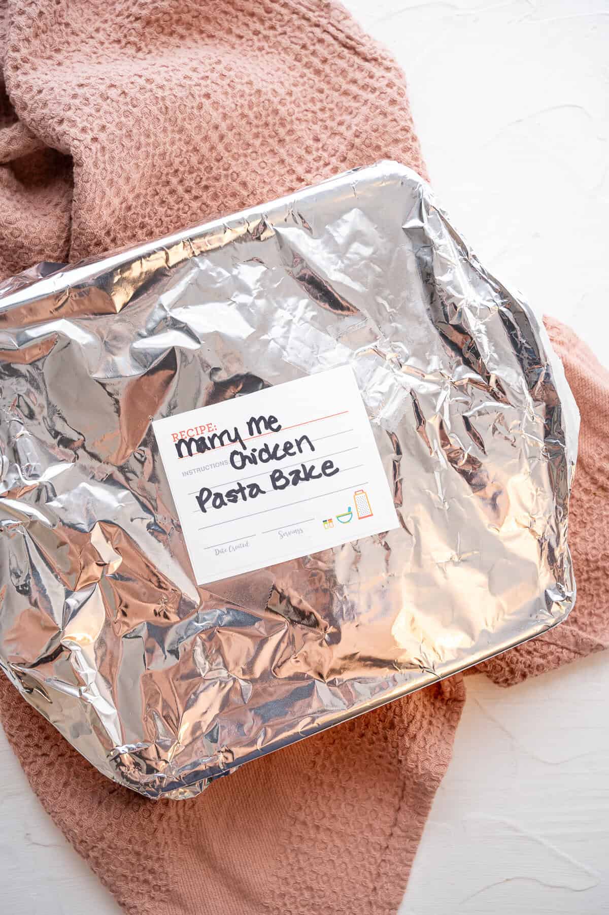 A 9x9 baking dish covered in foil with a freezer label saying, "Marry Me Chicken Pasta Bake".