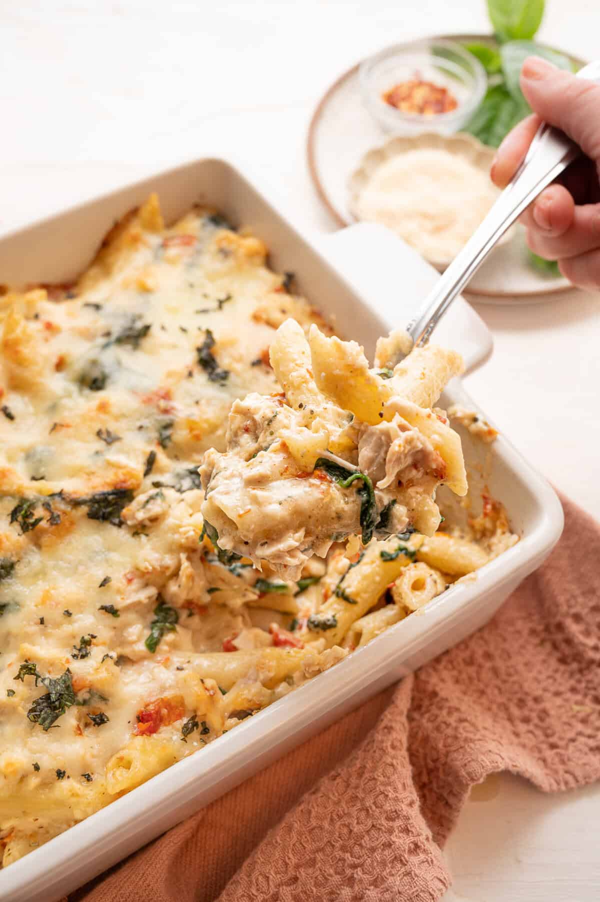 A serving of marry me chicken casserole being lifted from a baking dish.